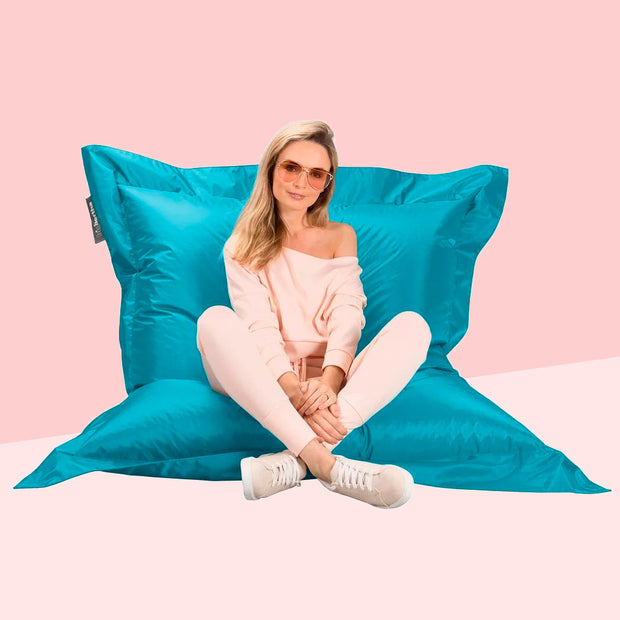 girl sitting on a Big Bertha Original xxl outdoor bean bag pillow in aqua blue
